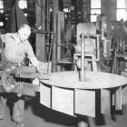 Worker using a pneumatically powered squeeze riveter to assemble a rotor.